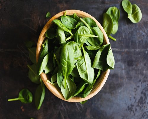 Bowl of freshly washed green spinach leaves on a kitchen counter